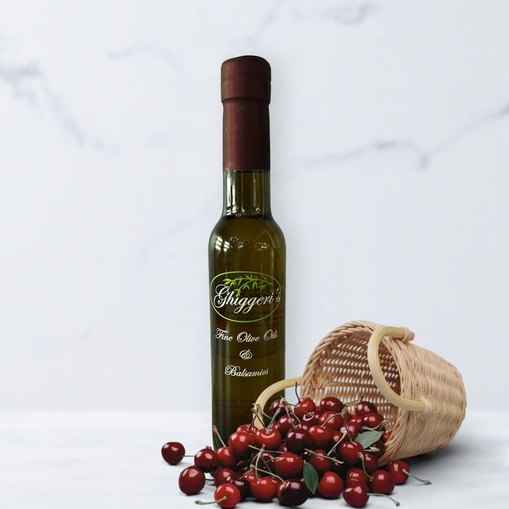 Black cherry balsamic vinegar bottle with ripe dark cherries and deep red balsamic drizzle

