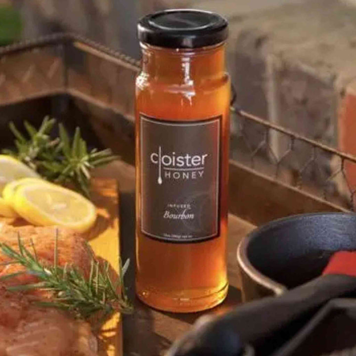 A jar of Cloister Bourbon Infused Honey, rich golden-honey with bourbon essence.