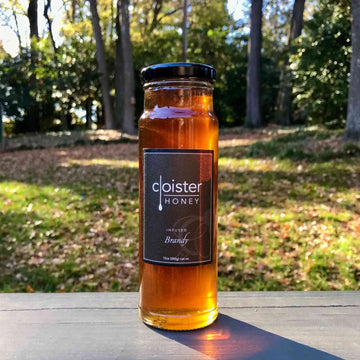 A jar of Cloister Brandy Infused Honey with rich golden hue.