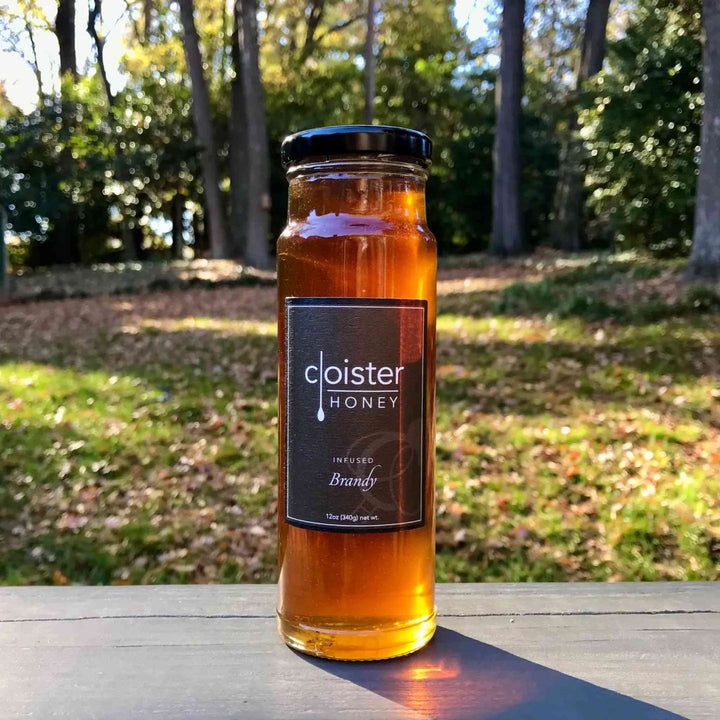 A jar of Cloister Brandy Infused Honey with rich golden hue.
