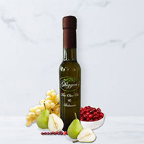 Bottle of white balsamic vinegar with fresh pears, and a bowl of fresh cranberries on a light background