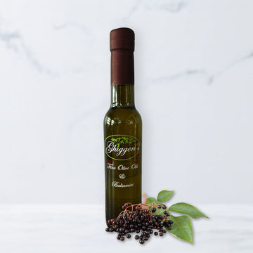 Elderberry balsamic vinegar bottle with fresh elderberries and deep purple tones