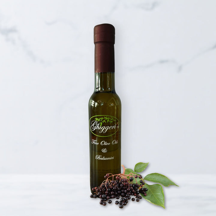 Elderberry balsamic vinegar bottle with fresh elderberries and deep purple tones