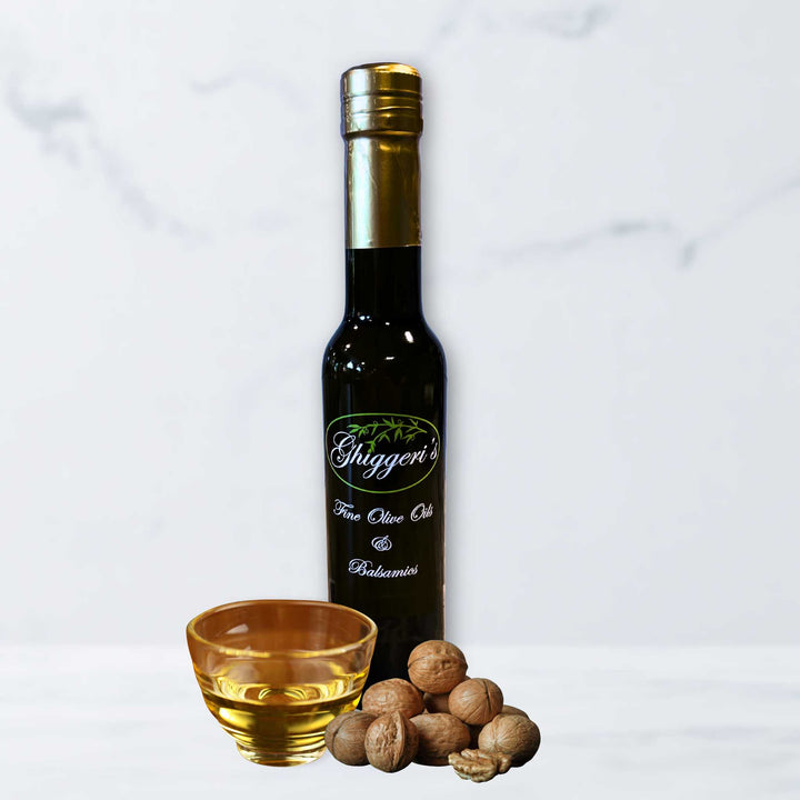A bottle of Ghiggeri's Roasted Walnut Oil with whole and halved toasted walnuts on a dark, elegant background.