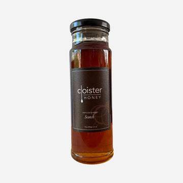 Jar of Scotch Infused Honey, amber-colored with smoky undertones.